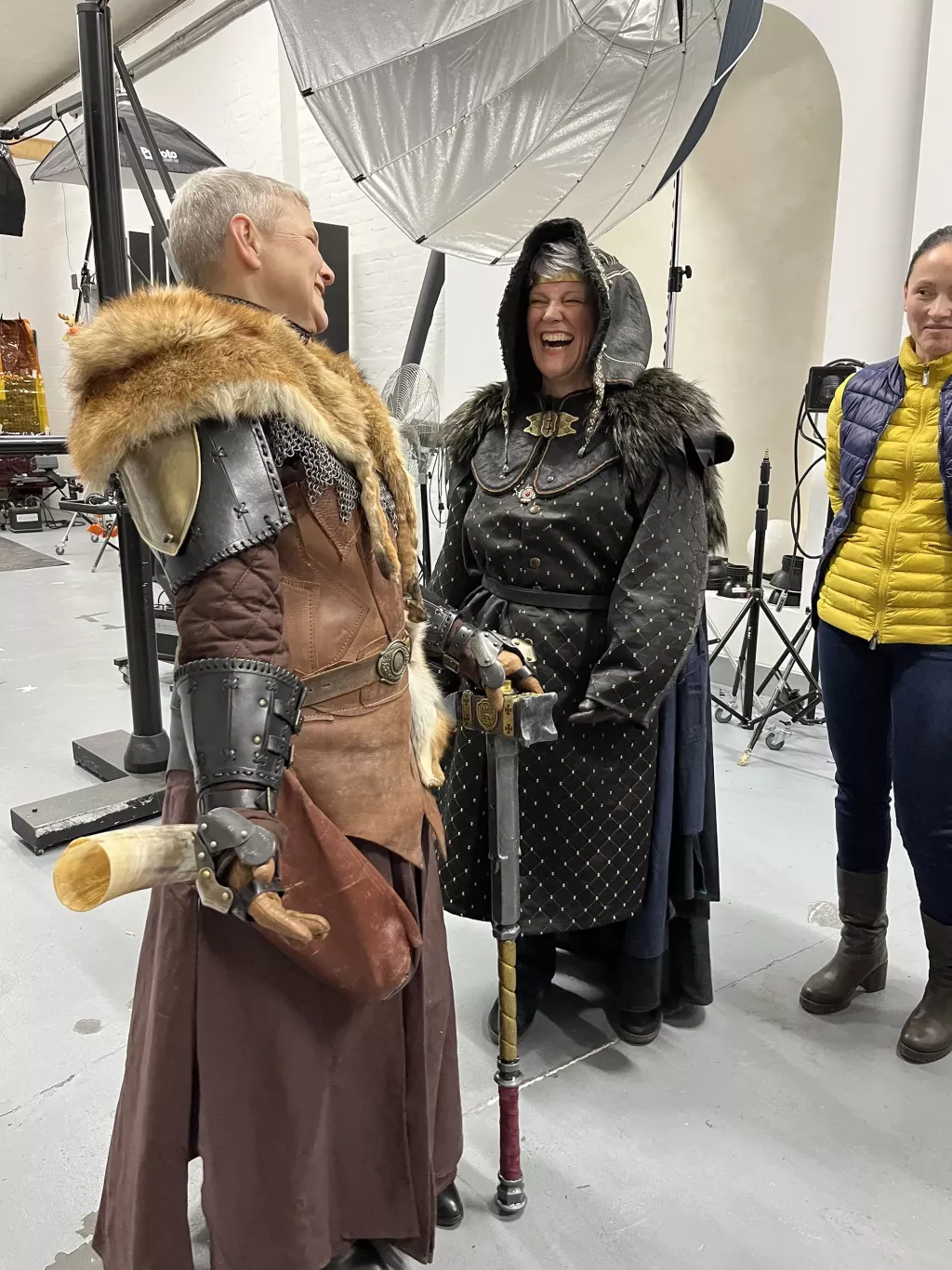 Zwei Frauen in Ritterrüstungen lachen während eines Fotoshootings.