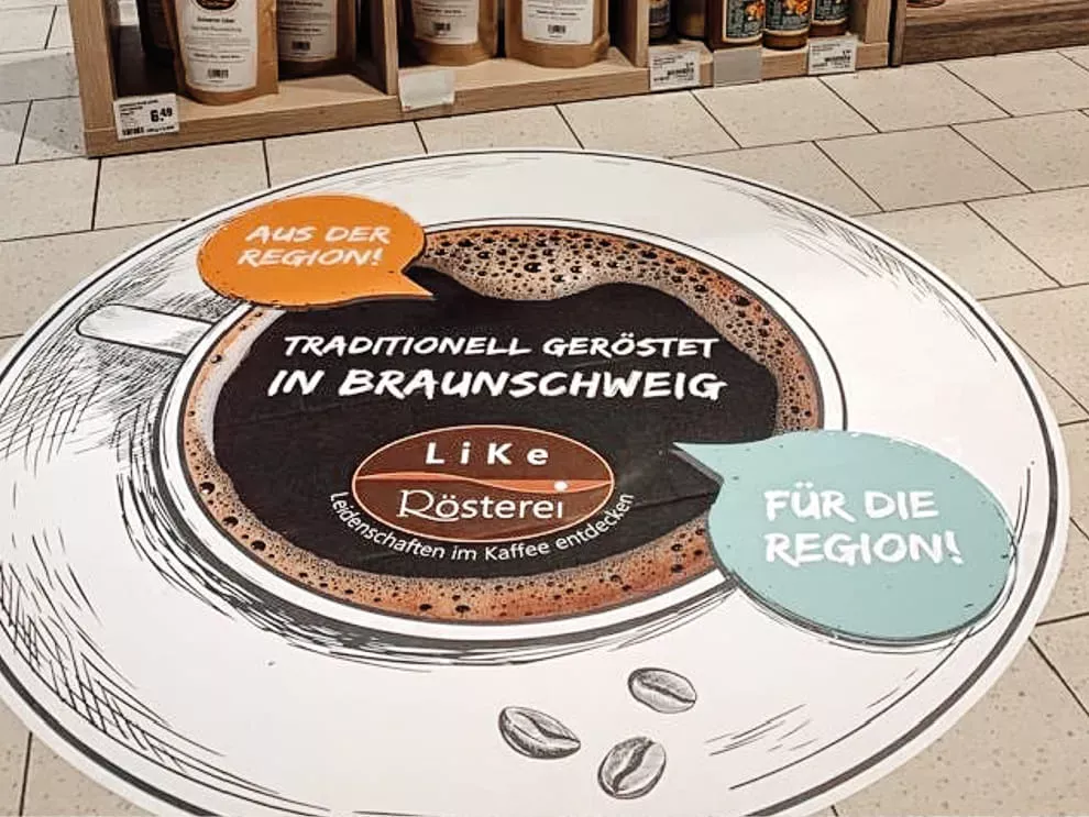 Ein Fußbodenaufkleber wirbt in einem Markt für die Kaffeerösterei LiKe.