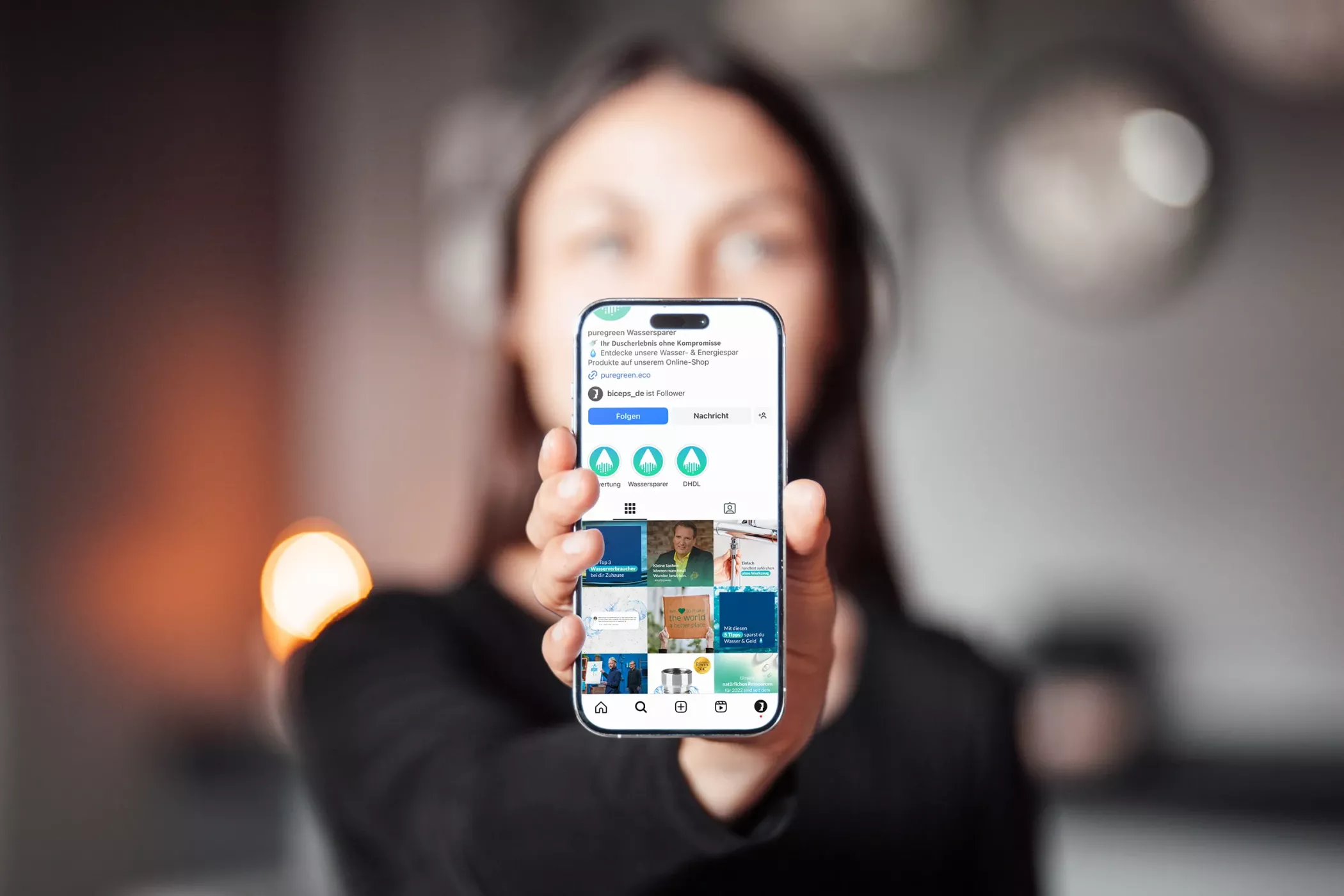 Weibliche Person hält ein Smartphone in der Hand mit dem geöffneten Instagram Profil von Puregreen.
